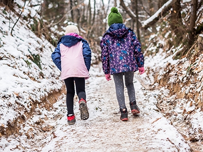 Children hiking in snow mountains forest on family trip.