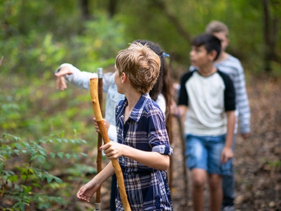 Girl Leading Her Friends Through a Trail in the Woods stock photo