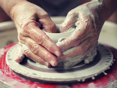 Potter's Wheel - Throwing Pottery A potter works on a clay bowl on a spinning potter's wheel.