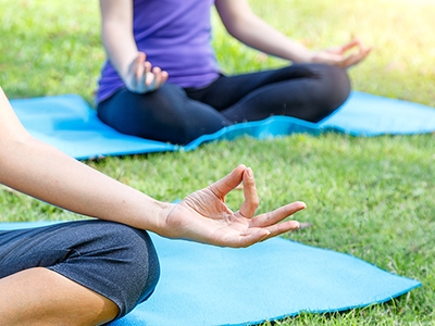 Cropped image group of young woman meditating in a yoga on grass in the park, yoga and healthy lifestyle concept