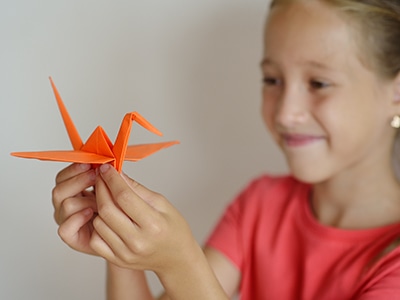The girl puts origami from paper. Lesson of origami