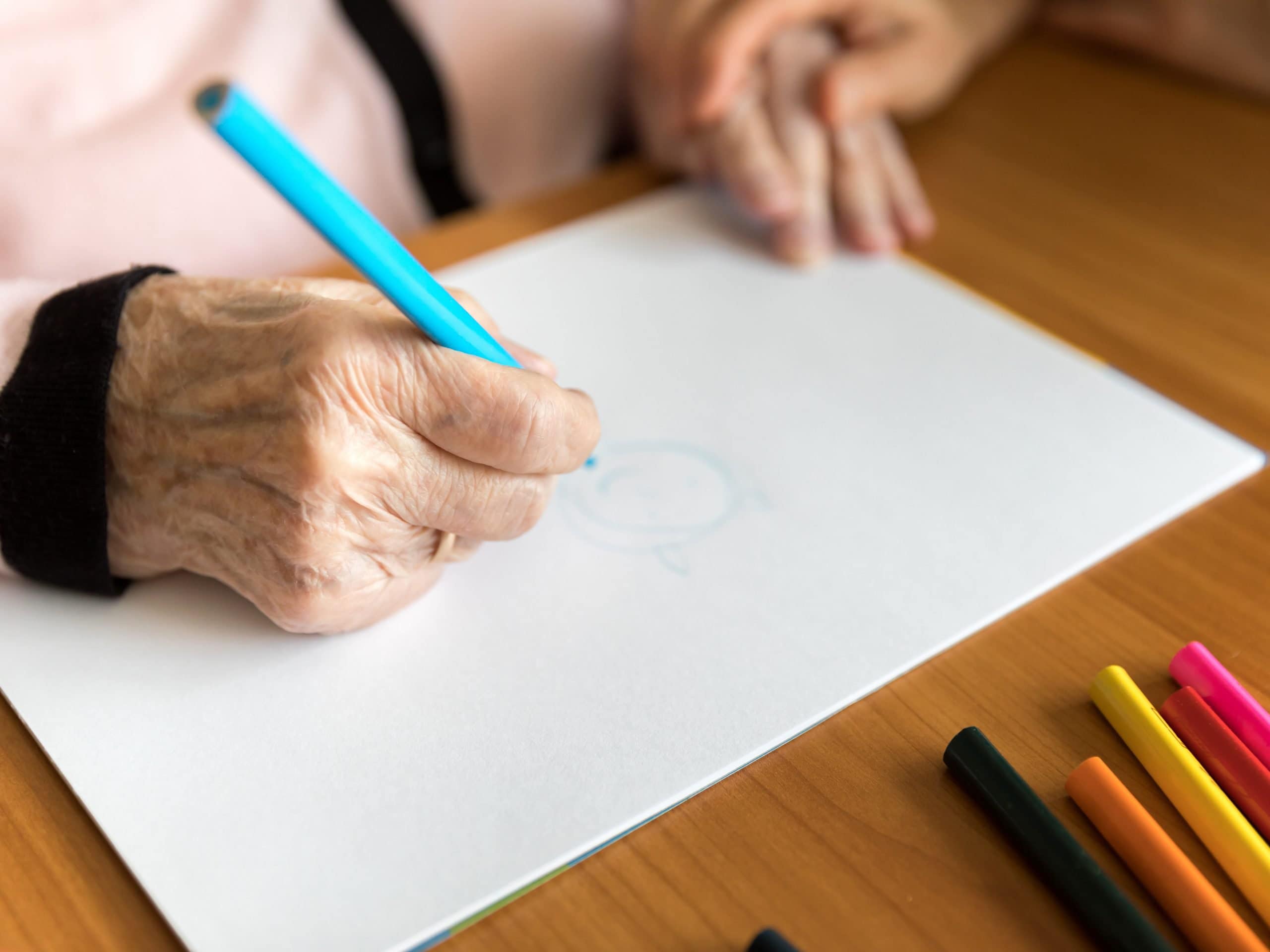 Senior woman drawing on white paper