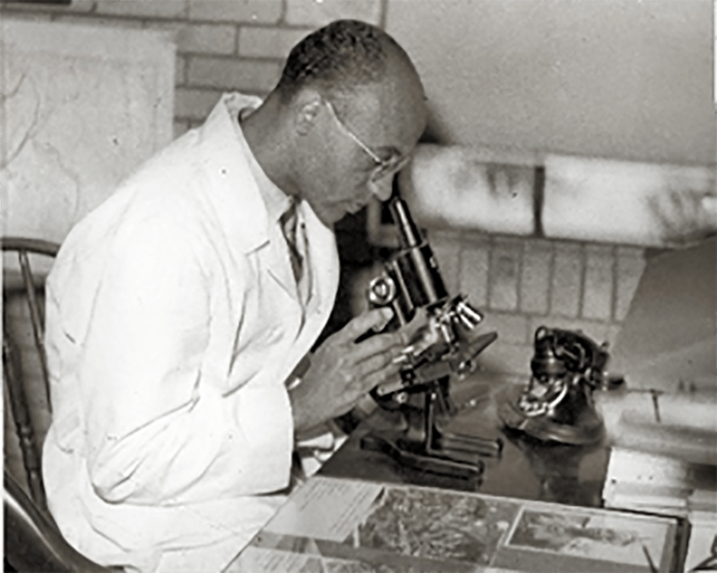 African American man looking into a microscope.